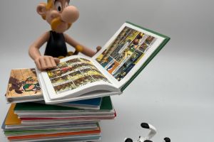 Asterix and Dogmatix with a stack of albums
